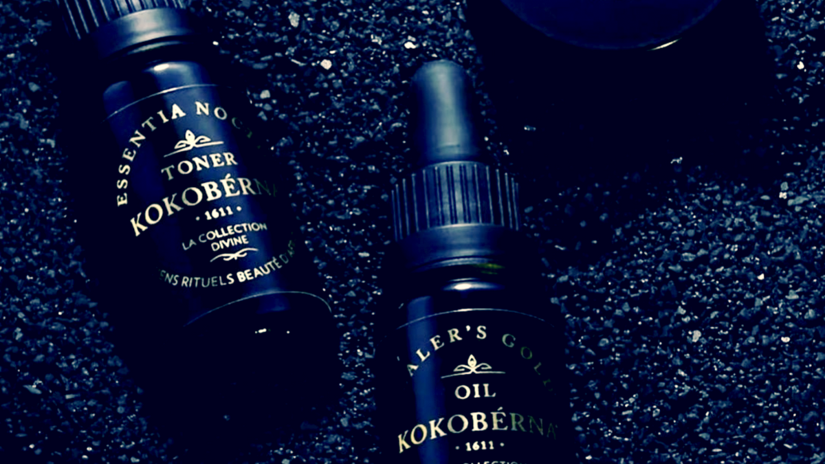 KOKOBÉRNA face preparations, including HEALER’S GOLD™ Serum and Oil, arranged on a gold tray.