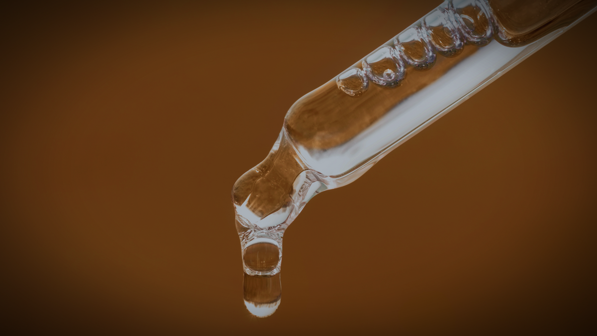 Clear peptide complex drops falling from a glass pipette against a warm brown background, representing the Bioactive Amino Peptide Complex™.
