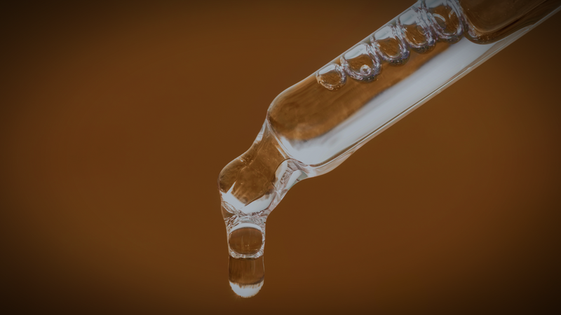 Clear peptide complex drops falling from a glass pipette against a warm brown background, representing the Bioactive Amino Peptide Complex™.